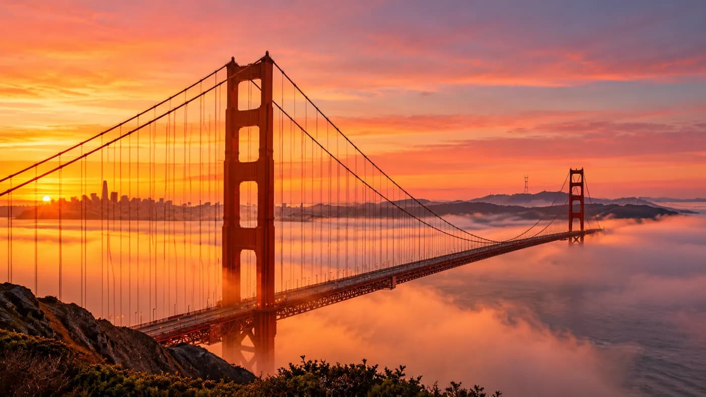 The Golden Gate Bridge at sunset, fog over the bay