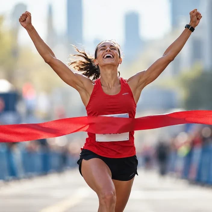 A runner breaking the finish-line tape, arms raised